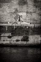 Couple sitting by the Venetian canal, lost in their moment.