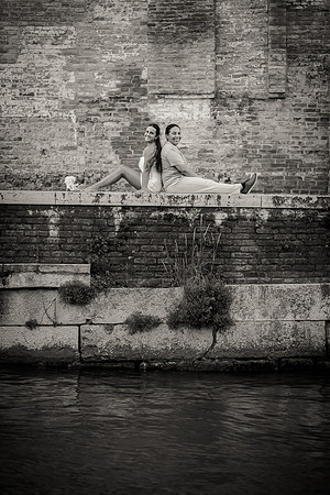 Couple sitting by the Venetian canal, lost in their moment.