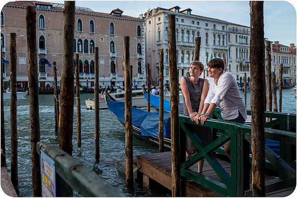 Lesbian woman sitting near a Venetian canal, reflecting during a summer afternoon.