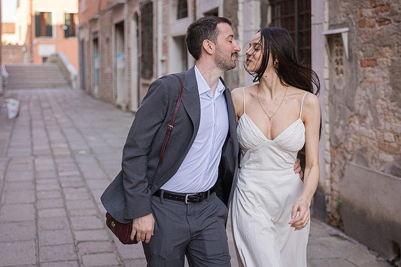 Engaged couple walking and laughing on a Venetian street.