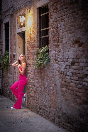 Model posing in a Venetian alleyway at night.