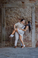 Same-sex couple sharing a playful embrace under an old Venetian arch.