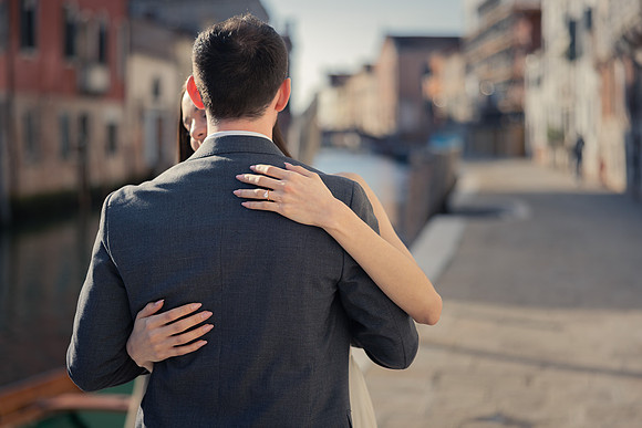 Couple embracing on a Venice walkway beside the canal.