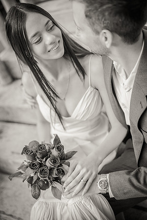 Black and white portrait of engaged couple sitting closely.