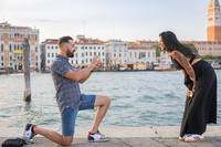 Romantic proposal moment as groom kneels during golden sunset in Venice.