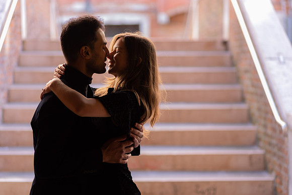 Couple standing on a staircase in Venice, holding each other closely.