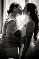 Same-sex couple kissing in a black and white engagement portrait.