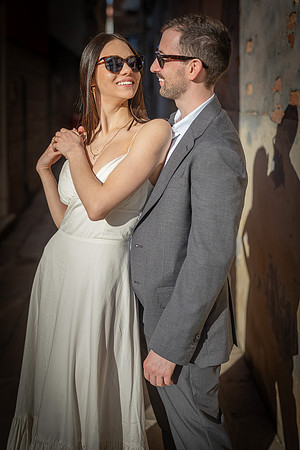 Engaged couple posing in sunglasses against a wall in Venice.