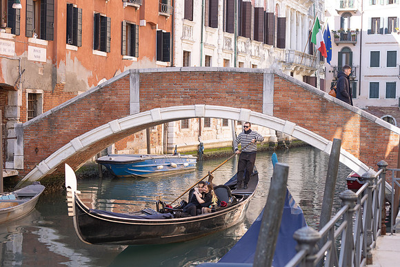 Couple standing on a Venetian bridge, gazing into each other’s eyes.