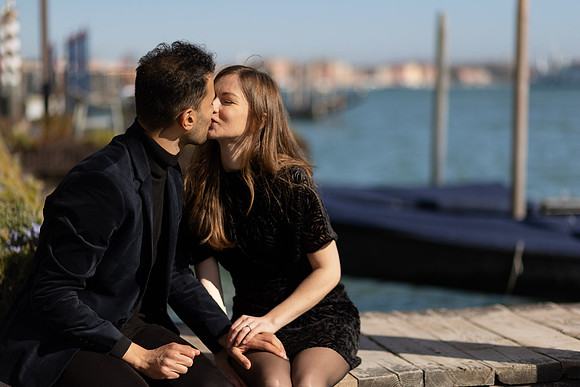 Couple sitting by the water, admiring the Grand Canal in Venice.
