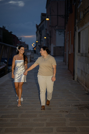 Same-sex couple walking hand in hand through the quiet Venetian streets.