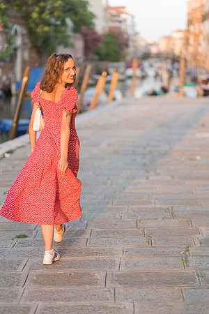 Model walking in sunlit street in Venice.