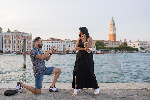 Couple laughing mid-proposal at Punta della Dogana, sunset glow.