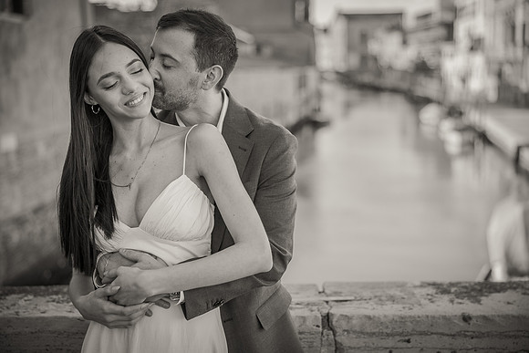 Romantic couple near a canal in Venice, softly focused.