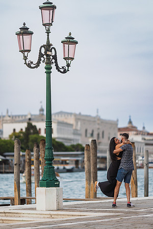 Engaged couple kissing along the Punta della Dogana promenade.