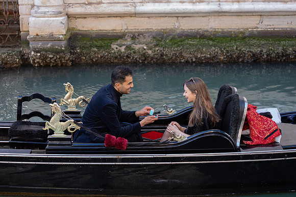 Couple sitting in a gondola, sharing a romantic moment in Venice.