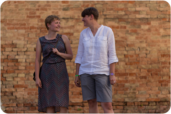 Lesbian couple holding hands while walking through the streets of Venice.