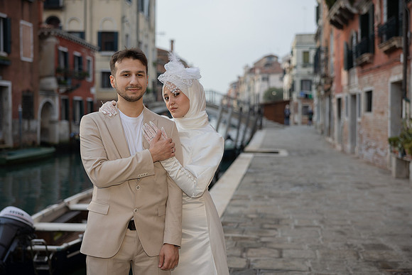 Engaged couple posing with historic Venice bridges in the background.
